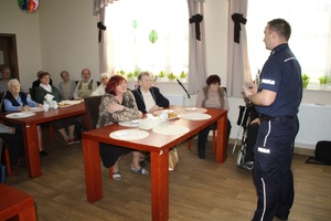 Policjant rozmawia z seniorami o kopercie życia