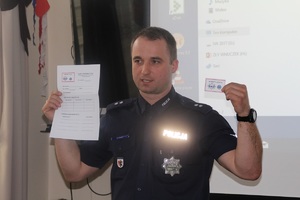 Policjant prezentuje kopertę życia