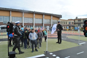 policjanci z dzieciakami w miasteczku ruchu drogowego
