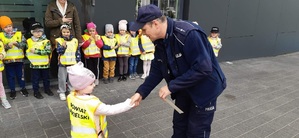 Policjant wręcza dziecku opaskę odblaskową