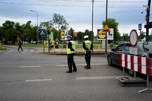 dwaj policjanci ruchu drogowego stoją przy skrzyżowaniu i obserwują ruch na drodze