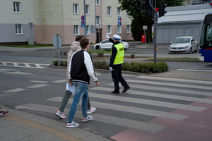 Policjant ruchu drogowego daje sygnał pieszym do przejścia przez przejście dla pieszych