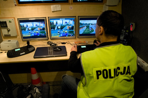 Policjant w Mobilnym Centrum Monitoringu obserwuje na monitorze wizje z kamer