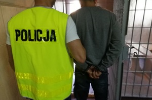 Policjant prowadzi zatrzymanego do aresztu