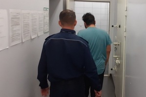 policjant stoi w korytarzu wraz z zatrzymanym