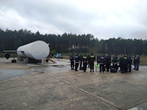 Policjanci stoją przed trenażerem symulującym statek powietrzny