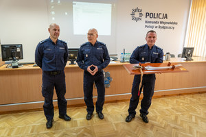 trzech policjantów stoi na środku sali konferencyjnej