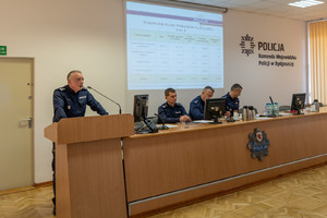 Komendant przemawia do policjantów siedzących przy ławkach