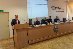 Komendant przemawia do policjantów siedzących przy ławkach