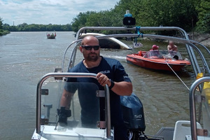 Policjant prowadzi motorówkę holującą łódż