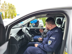 Jeden z policjantów prezentuje 35-latkowi radiowóz