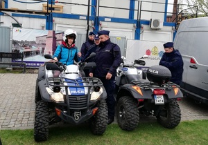 Teren Wyspy Młyńskiej. Tło stanowią banery promujące Bydgoszcz. Policjanci stoją przy pojazdach służbowych- quadach. Na jednym z pojazdów siedzi kobieta ubrana na niebiesko.
