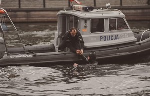 Teren  w rejonie Wyspy Młyńskiej i rzeki Brdy w Bydgoszczy. Ujęcie z bliska, na którym widać jak policjant będący na policyjnej łodzi motorowej wyciąga z wody mężczyznę (fragment pokazu).