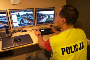 policjant monitoruje na kamerach mobilnego centrum monitoringu sytuacje przed stadionem