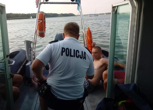 Policjant rozmawia z mężczyzną na łodzi.