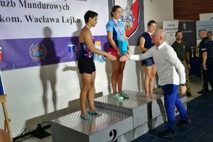 uczestniczki pływania stoją na podium i odbierają medale