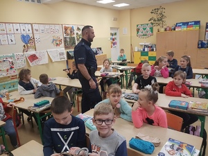 Policjant i dzieci podczas zajęć w klasie  szkolnej.