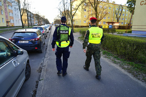 policjant z żandarmem idą chodnikiem i patrolują ulice
