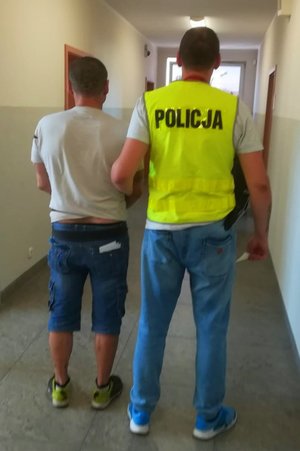 policjant trzyma zatrzymanego mężczyznę