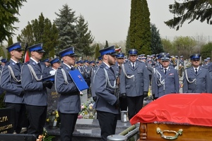 Policjanci stoją przy trumnie na cmentarzu