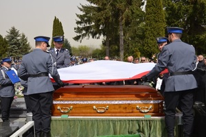 policjanci składają flagę państwową, która pokrywała trumnę Adama Łobockiego