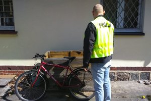 policjant stoi obok odzyskanego roweru