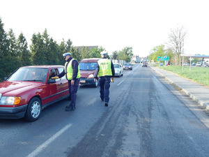 jeden z policjantów kontroluje trzeźwość kierowcy, a drugi funkcjonariusz podchodzi do kolejnego auta