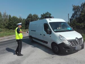 policjant zatrzymał auto do kontroli i wskazuje kierowcy miejsce gdzie ma zjechać