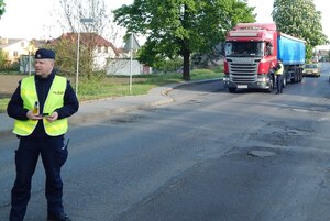 jeden z policjantów stoi na drodze z alkomatem, a drugi kontroluje kierowcę