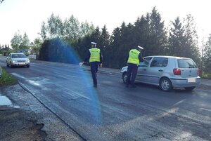 jeden z policjantów sprawdza trzeźwość kierującego, a drugi zatrzymuje auto do kontroli