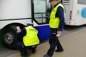 Policjanci kontrolują stan opon w autokarze.