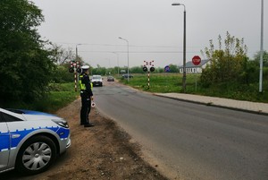 Policjant stoi w pobliżu przejazdu kolejowego.