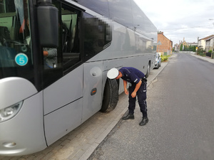 Policjant sprawdza w autokarze oponę.