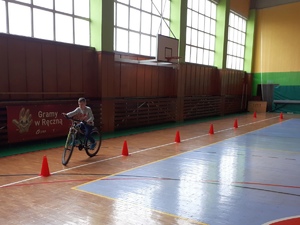 Jeden z uczniów jedzie na rowerze po torze przeszkód.