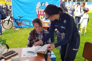 Policjantka pokazuje dziewczynce książkę ze znakami drogowymi