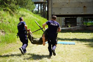 Dwóch policjantów biegnie trzymając manekina