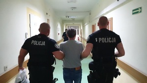 Policjanci prowadzą zatrzymanego korytarzem