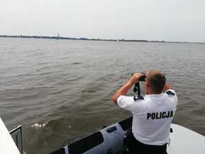 Policjant przez lornetkę obserwuje wody Zalewu Włocławskiego