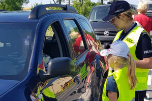 Policjantka wraz z uczennicą rozmawia z kierowcą granatowego auta