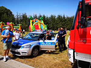 Policjanci na festynie w Cekcynie na pierwszym planie radiowóz