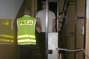 policjant prowadzi zatrzymanego za kratami