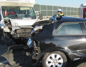 Roztrzaskany fiat, obok dostawcze auto, które wjechało w niego, a pomiędzy policjanci