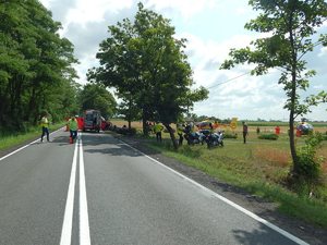 Policjanci robią oględziny miejsca wypadku, po prawej stronie dwa śmigłowce pogotowia