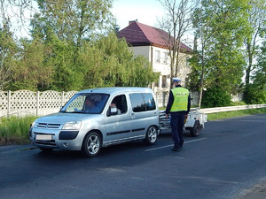 Funkcjonariusz ruchu drogowego kontroluje citroena z przyczepką