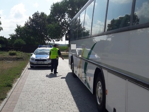 Policjant zmierza na tył autokaru, by sprawdzić silnik