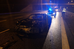 Policjanci pracują na miejscu kolizji, na pierwszym planie rozbite porsche