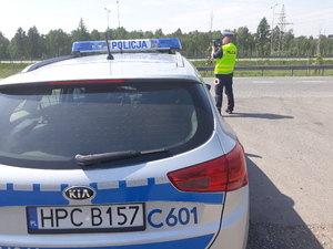 Policjant mierzy prędkość radarem obok radiowóz