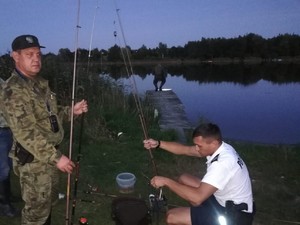 Policjant i strażnik rybacki zabezpieczają sprzęt kłusownika