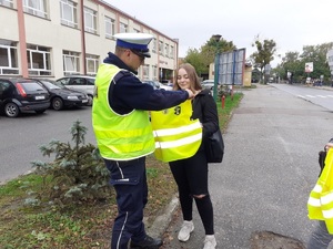 Policjant daje kamizelkę odblaskową pieszej