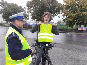 Policjant daje kamizelkę odblaskową  rowerzyście